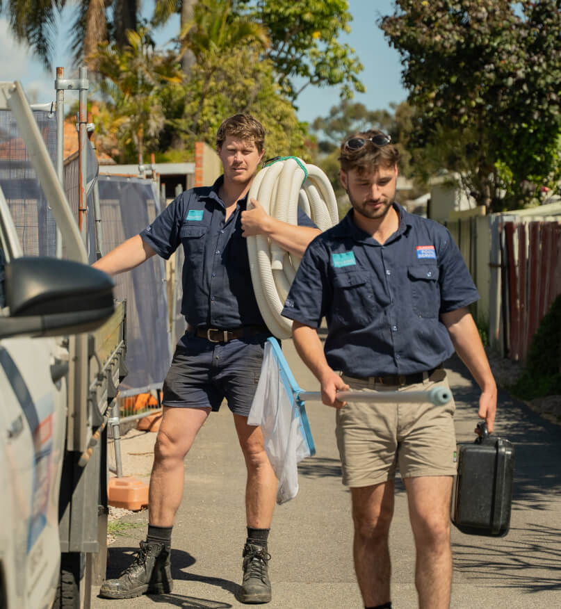 Two Claremont Pool Service technicians carrying a hose and tool case from their service ute