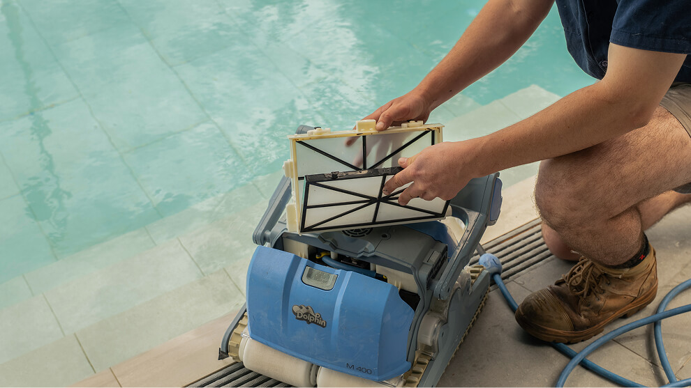 Close-up of hands removing the filter cartridge from a robotic pool cleaner