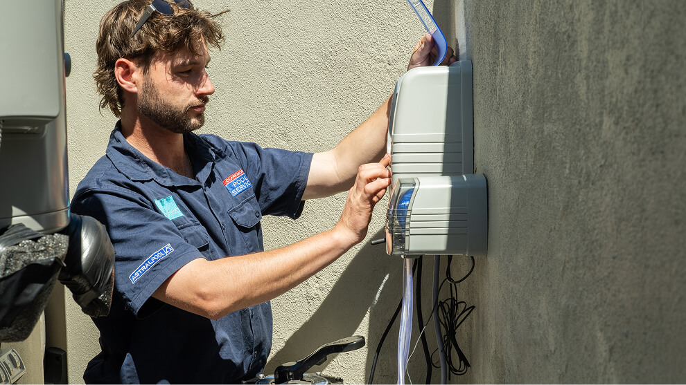 Technician adjusting a wall-mounted pool chlorinator control unit