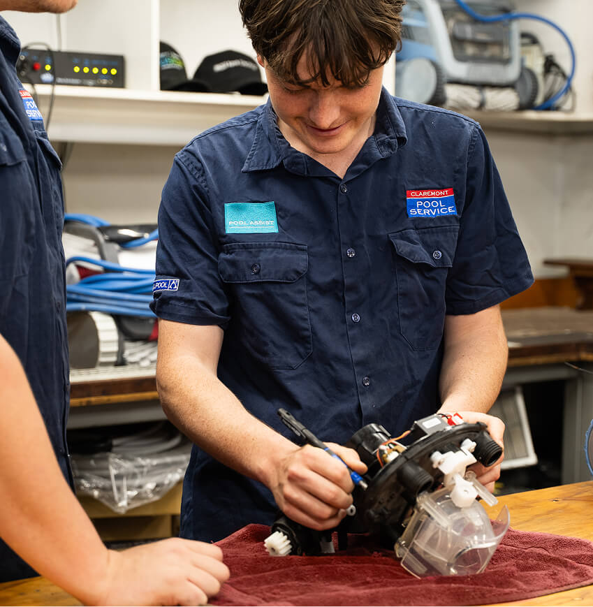Technician fitting a new part to a pool pump on a workshop bench