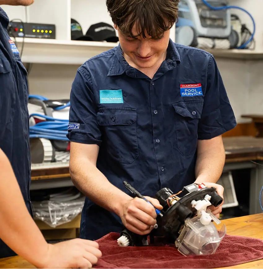 Technician fitting a new part to a pool pump on a workshop bench