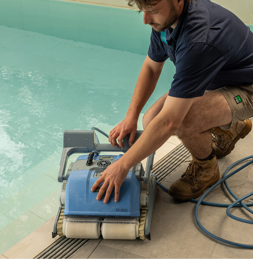 Technician servicing a robotic pool cleaner on the pool edge