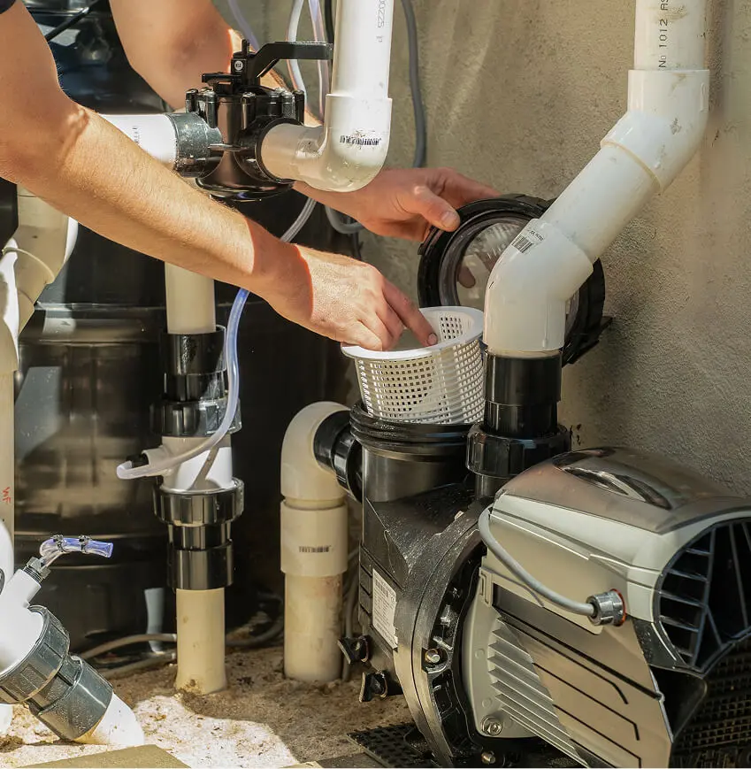 Technician removing the strainer basket from a pool pump beside the filtration plumbing