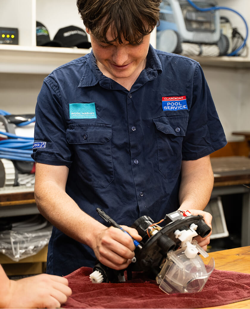 Technician fitting a new part to a pool pump on a workshop bench